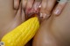 A close up of a woman's hand holding a corn on the cob.