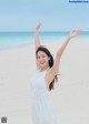 A woman standing on a beach with her arms outstretched.