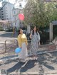 Two women standing next to each other holding balloons.