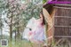 A woman in a pink dress holding an umbrella in a field.