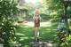 A woman walking down a path in a lush green park.