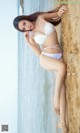 A woman in a white bikini laying on the beach.