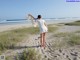 A woman in a white dress standing on a sandy beach.