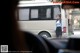 A woman standing in front of a white bus.