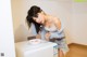 A woman standing next to a washing machine with a bowl of ice cream.