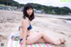 A woman in a blue bikini sitting on a beach towel.