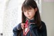 A young woman in a school uniform adjusting her tie.