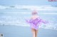 A woman with pink hair walking on the beach.